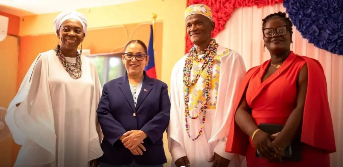 Group of four individuals posing together in a formal setting, showcasing cultural attire and accessories. The background features a colorful decoration with red, white, and blue elements, possibly representing a national theme.