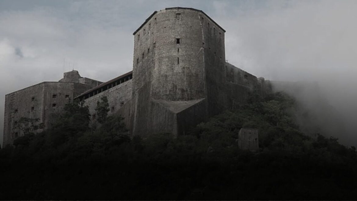 Historic stone fortress perched on a hillside, surrounded by mist and greenery, showcasing a blend of architectural strength and natural beauty.