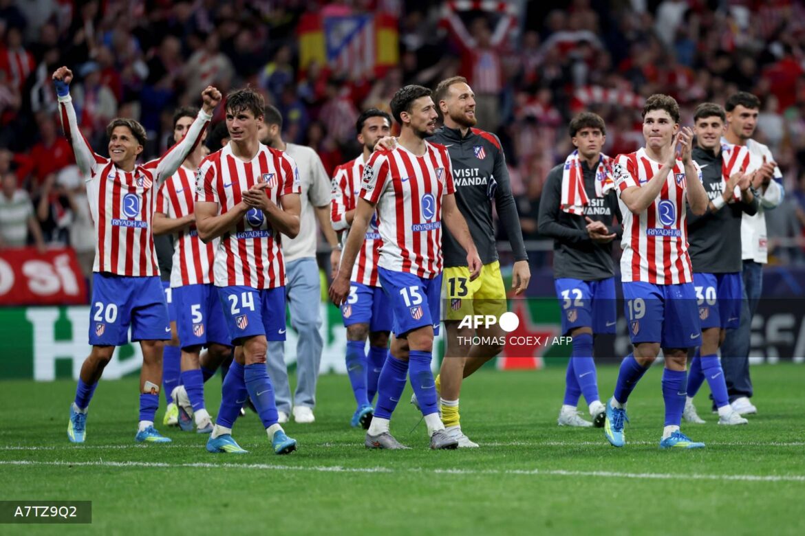 Atletico Madrid players celebrate a victory, showing team spirit and camaraderie on the field. The players, wearing their iconic red and white striped jerseys, express joy and appreciation towards the fans after a match.
