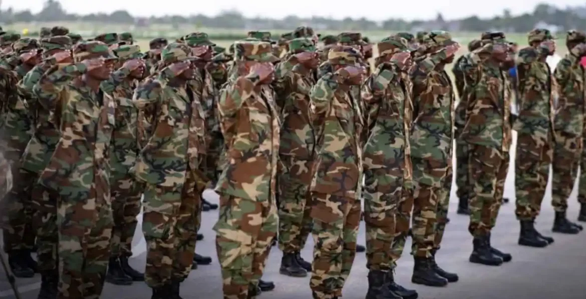 Military personnel in camouflage uniforms standing in formation, saluting during a ceremony outdoors.