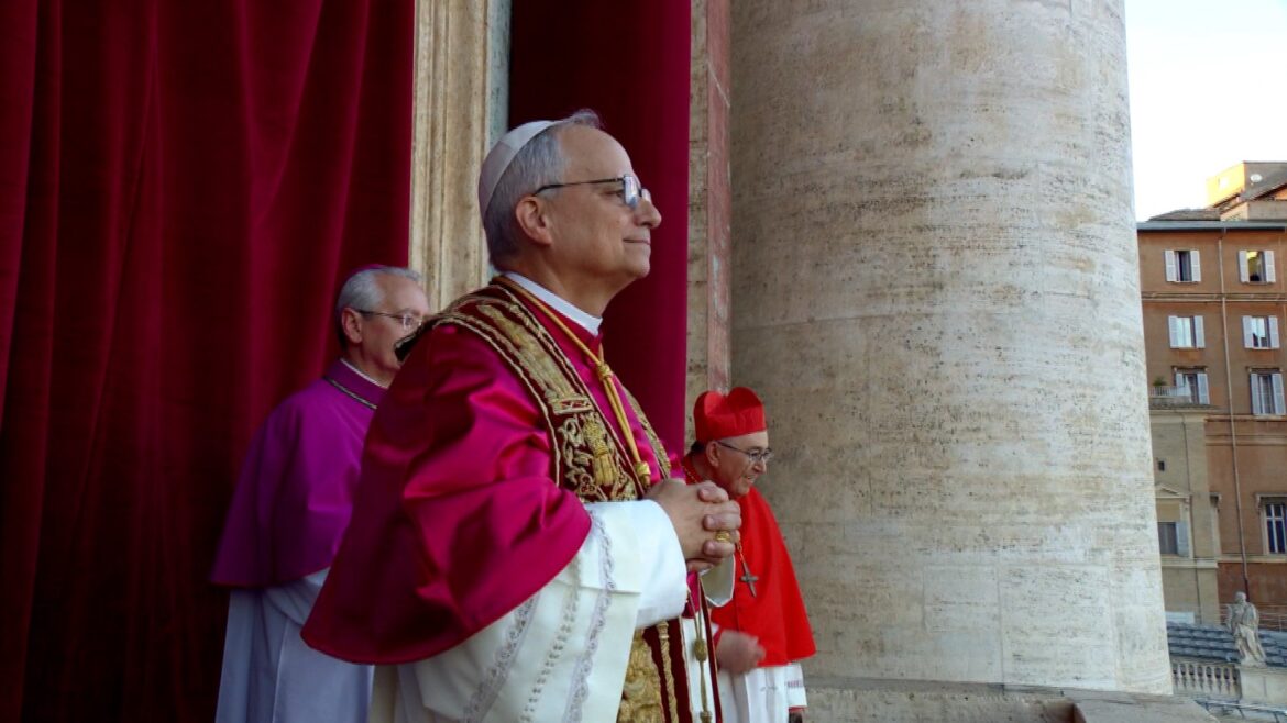 Pope and Cardinals in ceremonial attire standing at the Vatican, with red curtains in the background, during an official event. The image captures a moment of reflection and solemnity among the church leaders.