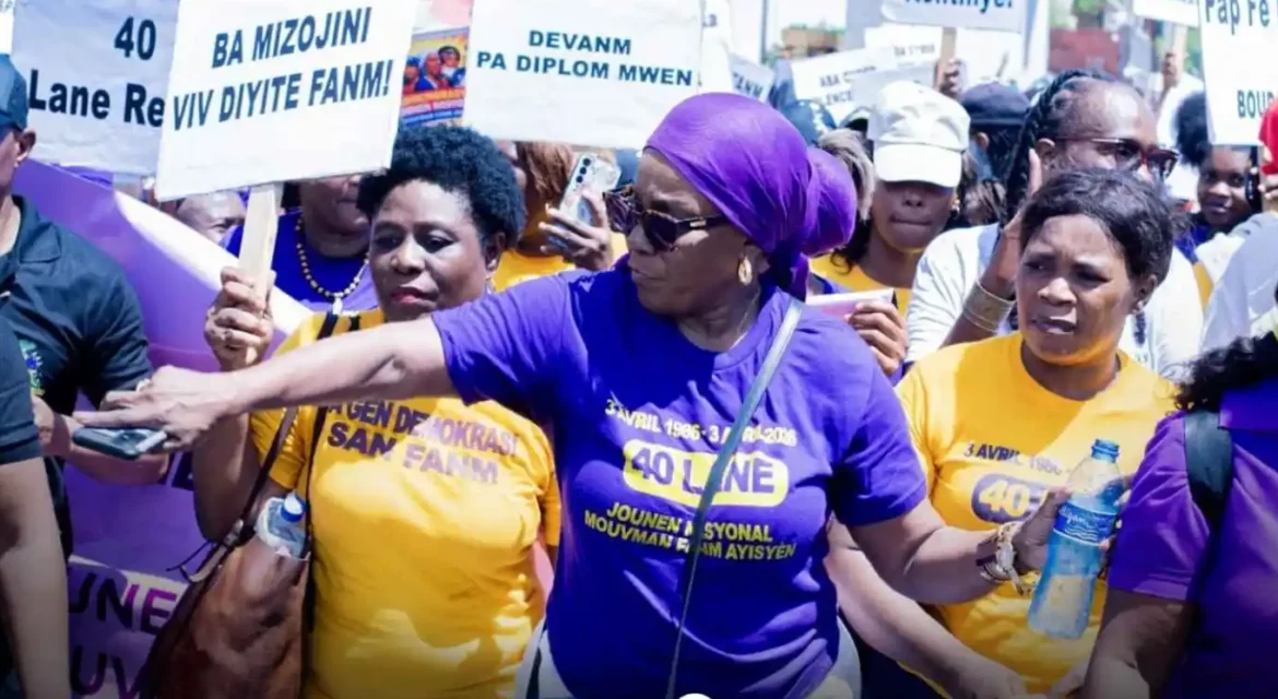 Women participating in a rally, wearing purple and yellow shirts, holding signs advocating for women's rights and empowerment. The scene captures a passionate demonstration for social change.